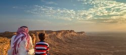 An arab man and his son sitting in Edge of the world, a natural landmark and popular tourist destination near Riyadh -Saudi Arabia.08-Nov-2019. Selective focus and background blurred.